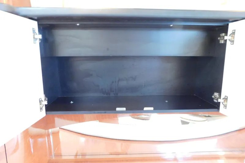 Slide: The Image of Open cabinet inside a 2005 Sea Ray 320 Sundancer boat, showcasing storage space. - 67