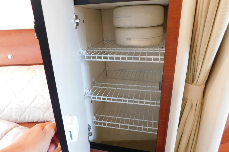 Slide: The Image of Open cabinet with wire shelves and cushions on a 2005 Sea Ray 320 Sundancer. - 71