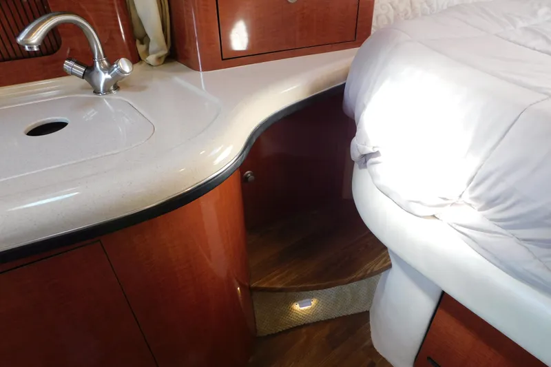 Slide: The Image of 2005 Sea Ray 320 Sundancer interior with sink, wooden cabinetry, and bed. - 77