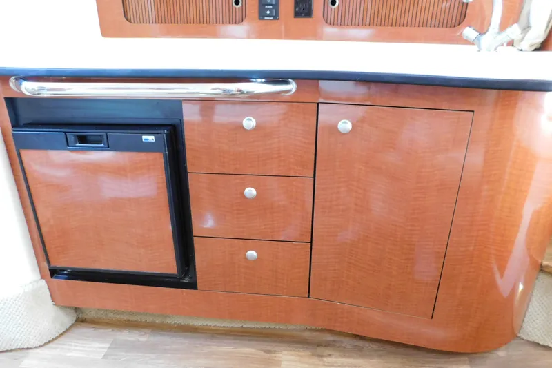 Slide: The Image of 2005 Sea Ray 320 Sundancer interior with wood cabinetry and mini fridge. - 81