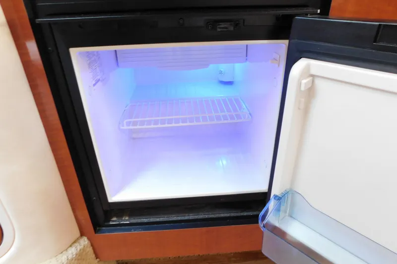 Slide: The Image of Open mini fridge with blue interior light on a 2005 Sea Ray 320 Sundancer boat. - 88
