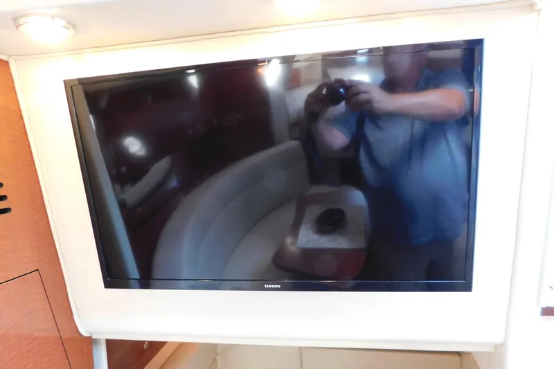 Slide: The Image of Flat-screen TV inside 2005 Sea Ray 320 Sundancer yacht cabin, reflecting interior seating area. - 92