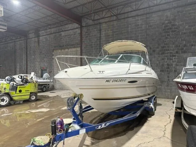 The Image of 1999 Sea Ray 215 Express Cruiser on trailer in indoor storage facility. - 1