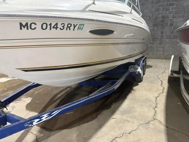 Slide: The Image of 1999 Sea Ray 215 Express Cruiser on blue trailer in indoor storage. - 4