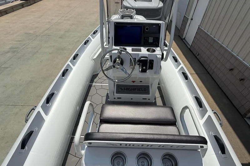 Slide: The Image of 2025 Highfield Sport 560 boat interior with steering console and seating, docked outdoors. - 17
