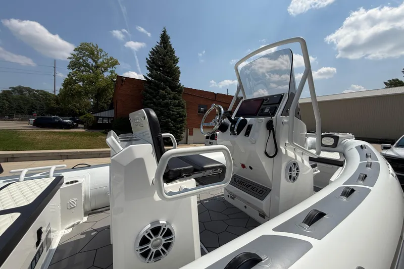 Slide: The Image of 2025 Highfield Sport 560 boat interior with steering console and seating, under a clear sky. - 27