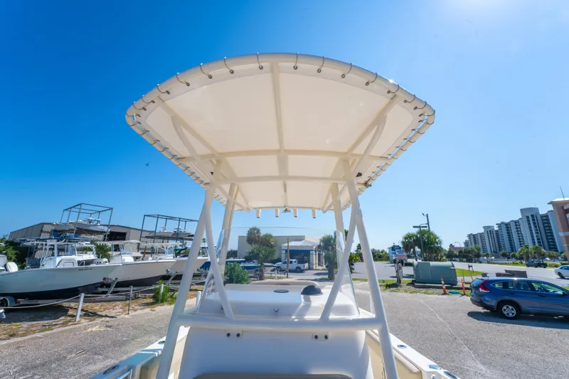 Slide: The Image of 2016 Cobia 201 Center Console boat with T-top, parked outdoors under clear blue sky. - 19