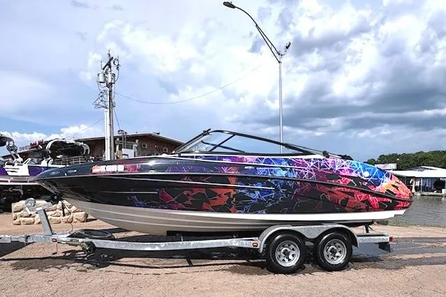 The Image of 2010 Yamaha Boats 212SS with vibrant geometric design on trailer, parked outdoors. - 0