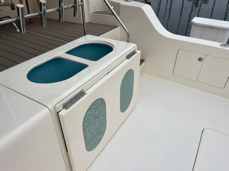 Slide: The Image of 1999 Mikelson Long-Range Luxury Sportfisher deck with storage compartments and rod holders. - 12