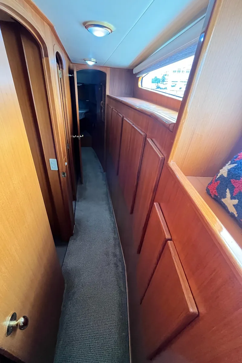 Slide: The Image of Hallway inside 1999 Mikelson Long-Range Luxury Sportfisher, featuring wood paneling and carpet flooring. - 37