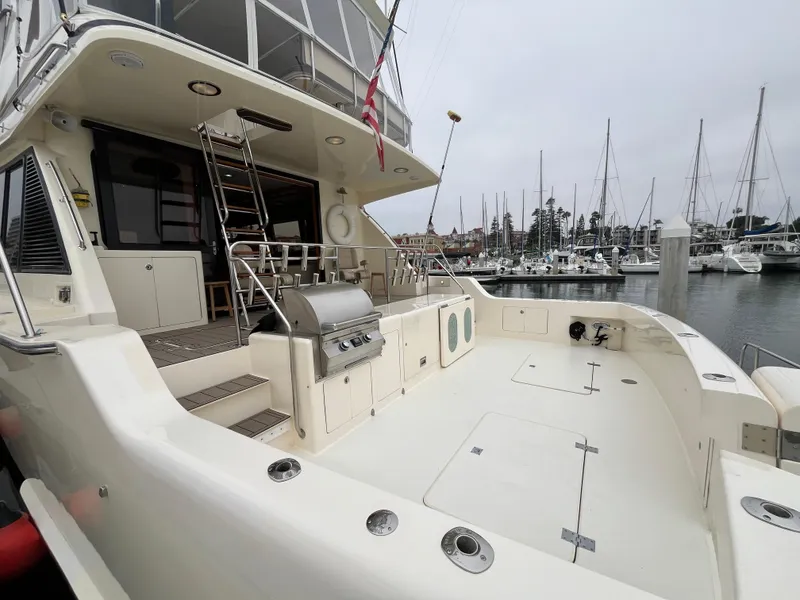 Slide: The Image of 1999 Mikelson Long-Range Luxury Sportfisher yacht docked, featuring spacious deck and grill. - 7