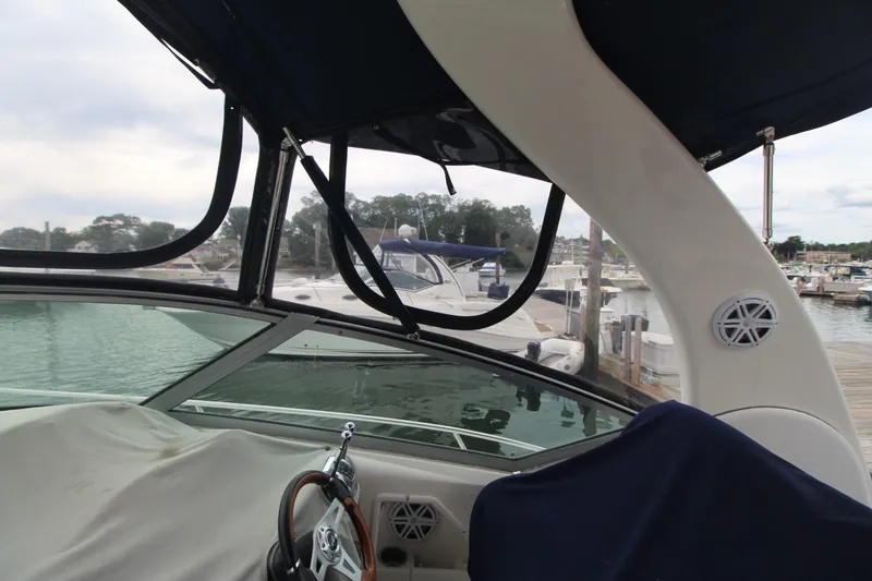 Slide: The Image of 2008 Sea Ray 340 Sundancer interior view at marina, showcasing helm and canopy. - 10