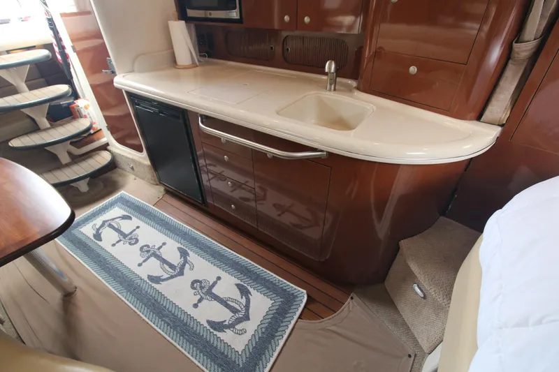 Slide: The Image of 2008 Sea Ray 340 Sundancer interior with kitchenette, sink, and nautical-themed rug. - 22