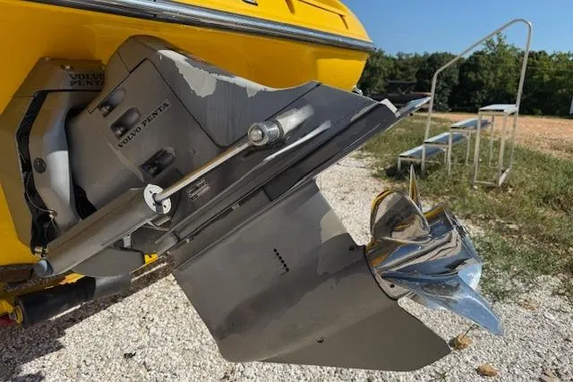 Slide: The Image of 2005 Crownline 210 LPX boat with Volvo Penta outdrive, yellow hull, parked on gravel. - 15