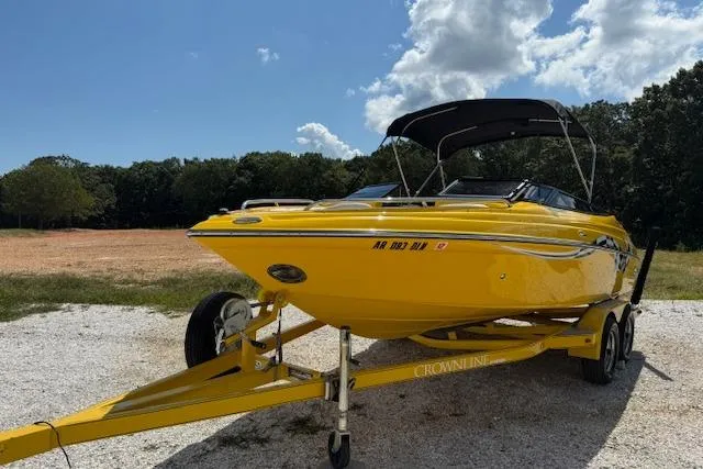 Slide: The Image of Yellow 2005 Crownline 210 LPX boat on trailer, parked outdoors under a blue sky. - 4