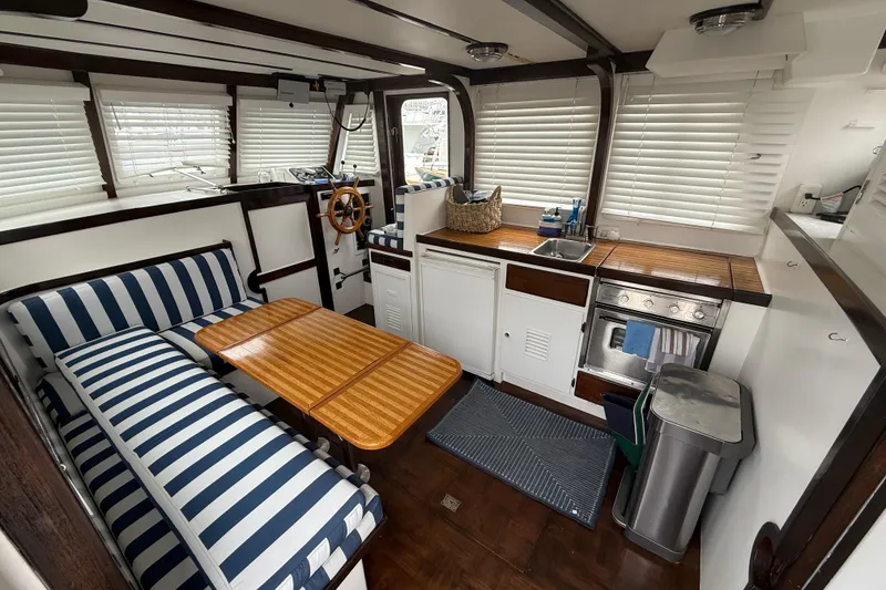 Slide: The Image of 1978 CHB 34 boat interior with striped seating, wooden table, and compact kitchen area. - 12