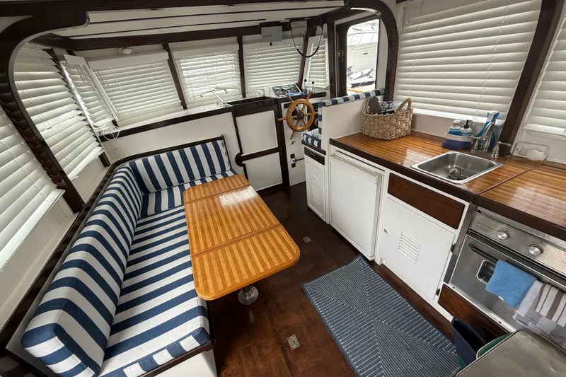 Slide: The Image of Interior of a 1978 CHB 34 boat with striped seating, wooden table, and compact kitchen. - 14