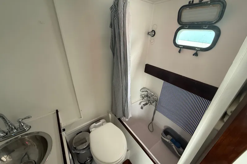 Slide: The Image of 1978 CHB 34 boat bathroom with sink, toilet, shower, and porthole window. - 22
