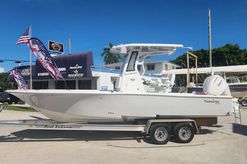 Slide: The Image of 2026 Tidewater 2500 Carolina Bay boat on trailer, displayed outdoors with flags and dealership signage. - 5