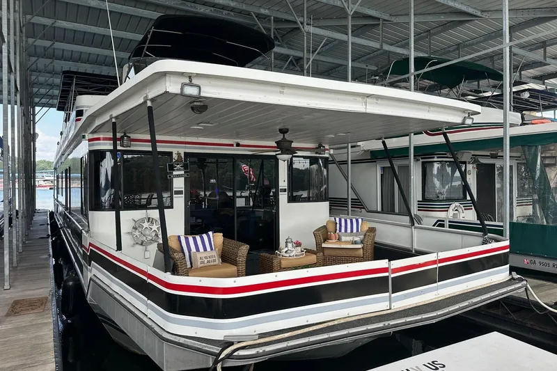 The Image of 1997 Stardust Cruisers 16x78 houseboat docked, featuring a cozy outdoor seating area. - 0