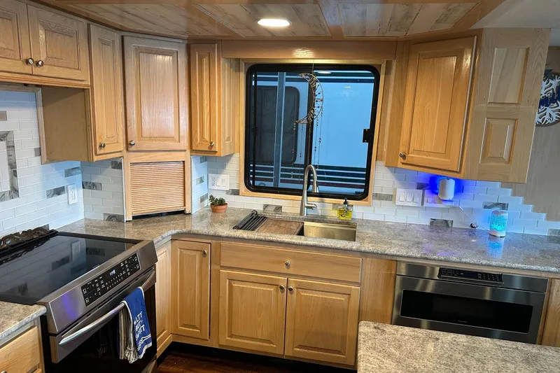 Slide: The Image of Kitchen interior of a 1997 Stardust Cruisers 16x78 houseboat with wooden cabinets and modern appliances. - 5