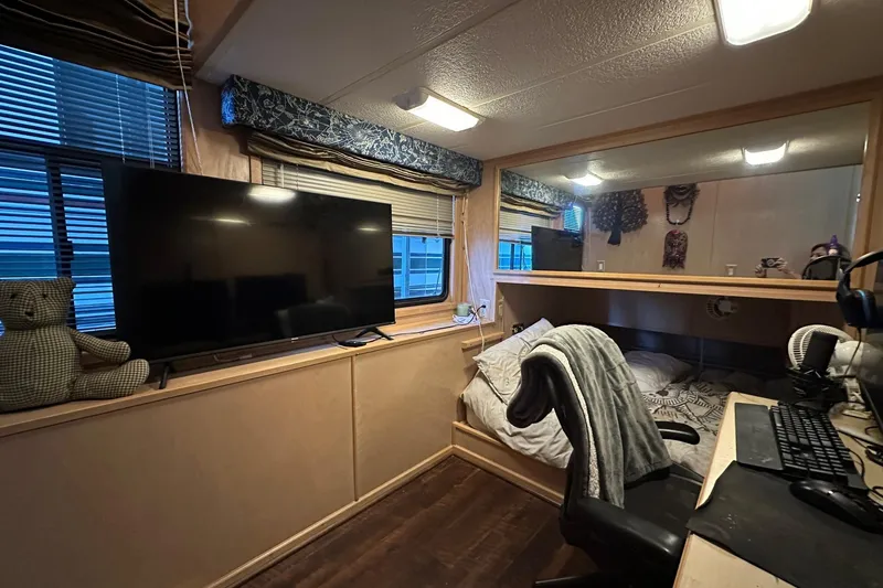 Slide: The Image of 1997 Stardust Cruisers 16x78 interior with TV, desk, and cozy bed setup. - 8