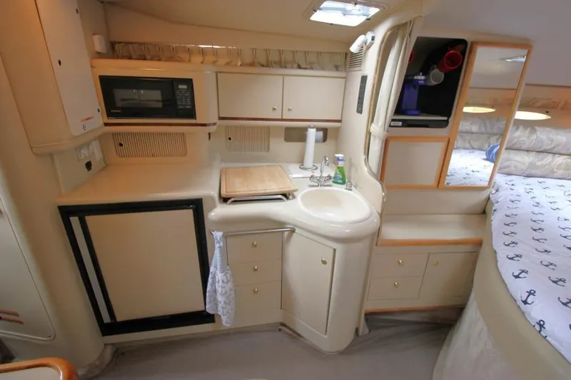Slide: The Image of 1998 Sea Ray 330 Sundancer interior kitchen with sink, microwave, and bed area. - 14