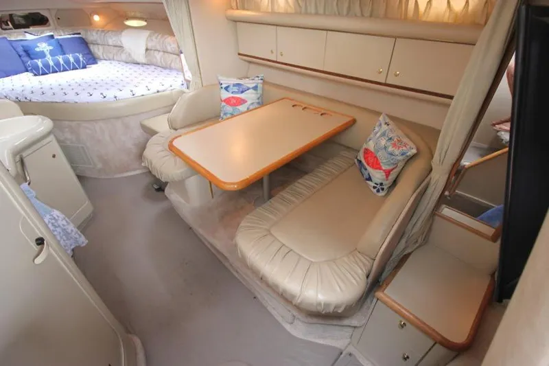 Slide: The Image of 1998 Sea Ray 330 Sundancer cabin interior with dining area and cozy sleeping space. - 16