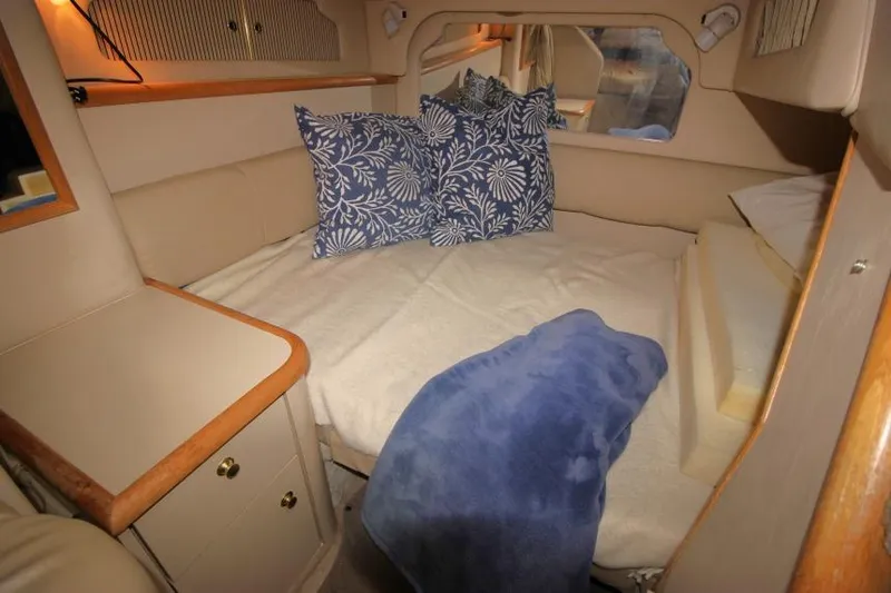 Slide: The Image of 1998 Sea Ray 330 Sundancer cabin with cozy bed, blue floral pillows, and soft blanket. - 17