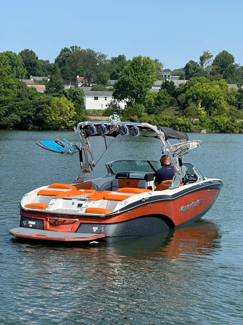 Slide: The Image of 2015 MasterCraft X23 boat on a lake with wakeboards. - 12