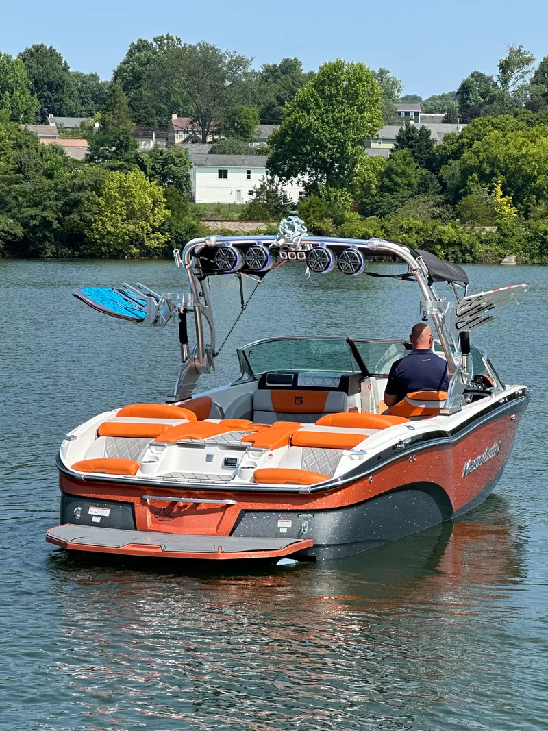 Slide: The Image of 2015 MasterCraft X23 boat on a lake with wakeboard tower and orange seating. - 15