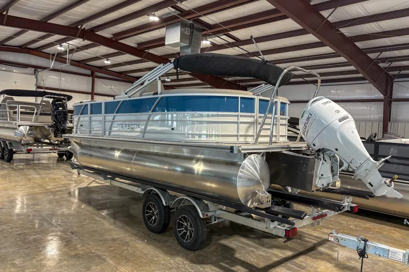 Slide: The Image of 2025 Trifecta 20RF LE pontoon boat in a showroom, featuring a Suzuki outboard motor. - 2
