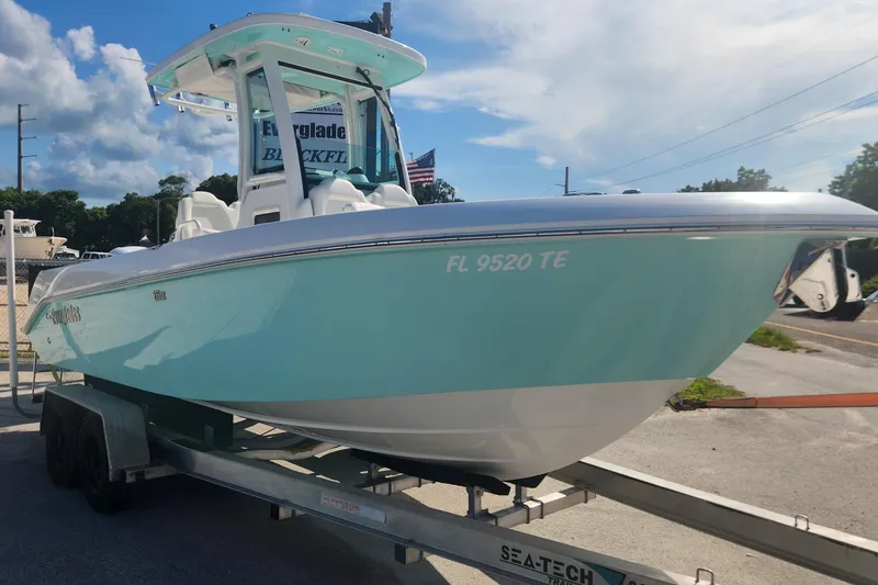 Slide: The Image of 2022 Everglades 235 Center Console boat on trailer, light blue hull, sunny day. - 3