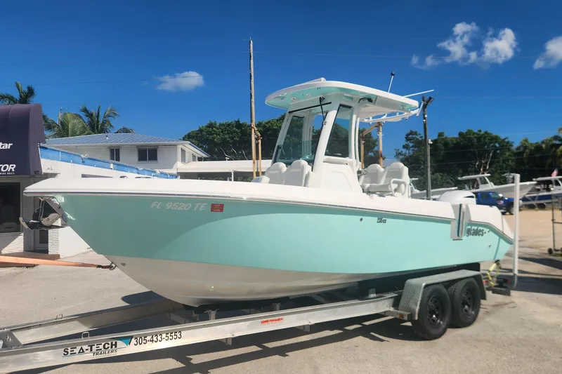 Slide: The Image of 2022 Everglades 235 Center Console boat on trailer, parked outdoors under clear blue sky. - 5