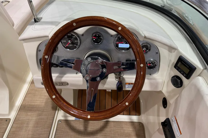 Slide: The Image of 2021 Chris-Craft Launch 23 dashboard with wooden steering wheel and instrument panel. - 14
