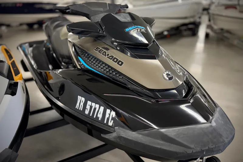 Slide: The Image of 2016 Sea-Doo GTX 155 jet ski in showroom, black and gold design. - 2