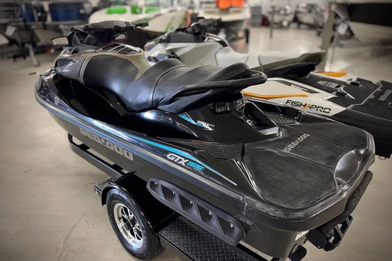 Slide: The Image of 2016 Sea-Doo GTX 155 jet ski in showroom, black with blue accents, on trailer. - 3