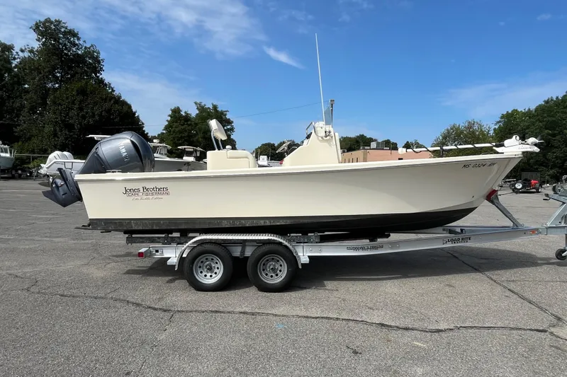 Slide: The Image of 2025 Jones Brothers 23 Cape Fisherman Lite Tackle boat on trailer, parked outdoors. - 1