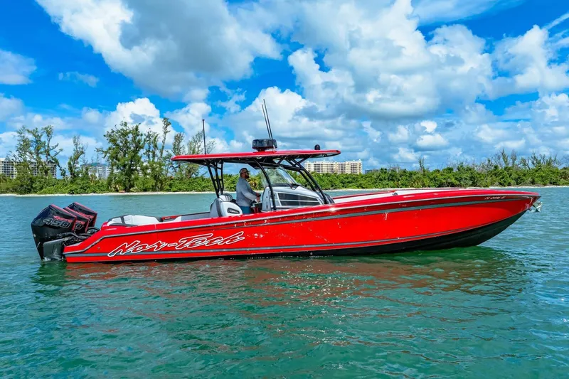 The Image of 2022 Nor-Tech 390 SS boat in vibrant red on clear blue water. - 1