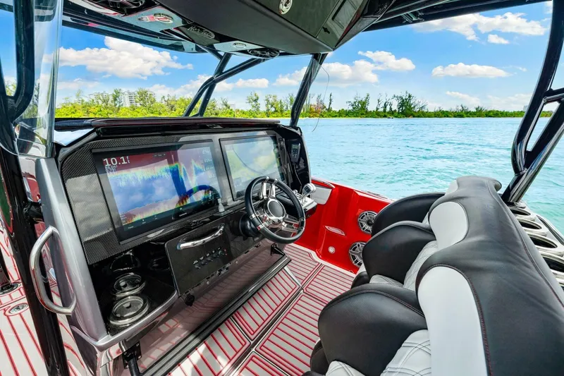 Slide: The Image of 2022 Nor-Tech 390 SS boat cockpit with advanced navigation screens and luxurious seating. - 12