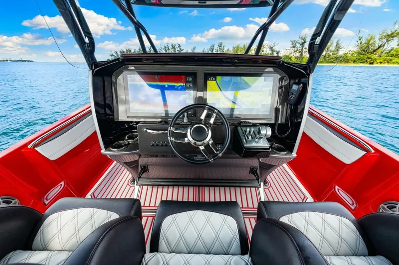 Slide: The Image of 2022 Nor-Tech 390 SS boat cockpit with modern navigation system, red and white interior. - 13