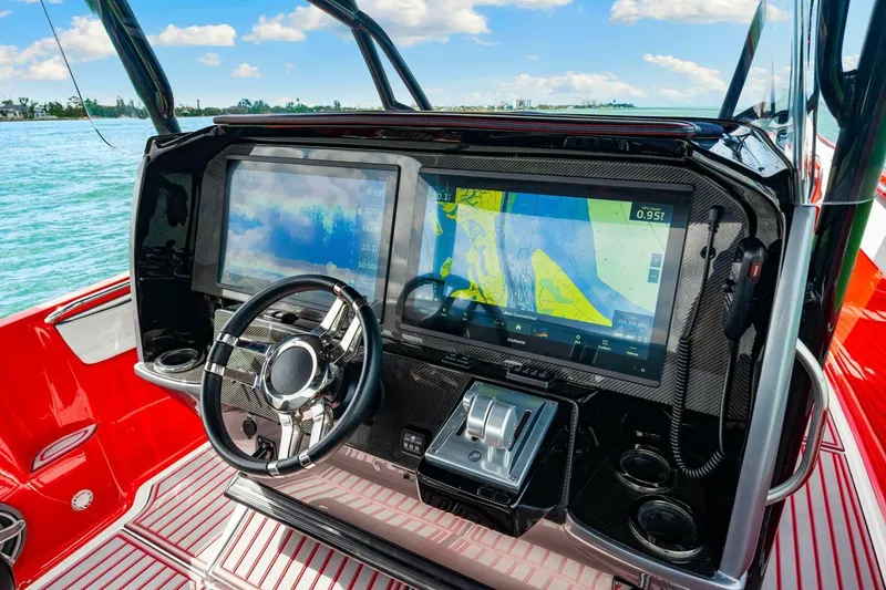 Slide: The Image of 2022 Nor-Tech 390 SS boat dashboard with advanced navigation screens and sleek steering wheel. - 14