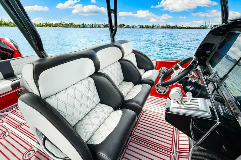 Slide: The Image of 2022 Nor-Tech 390 SS boat interior with luxury seating and modern dashboard on a sunny day. - 16