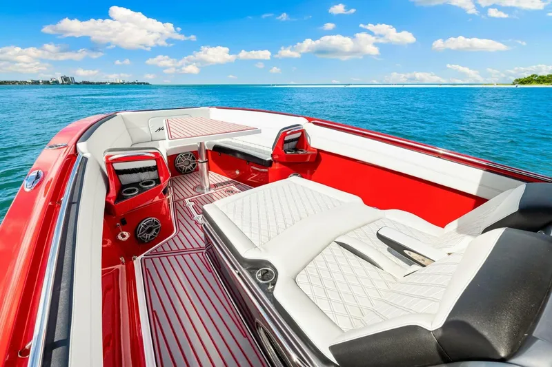 Slide: The Image of 2022 Nor-Tech 390 SS boat interior with red and white seating, on a sunny day at sea. - 32