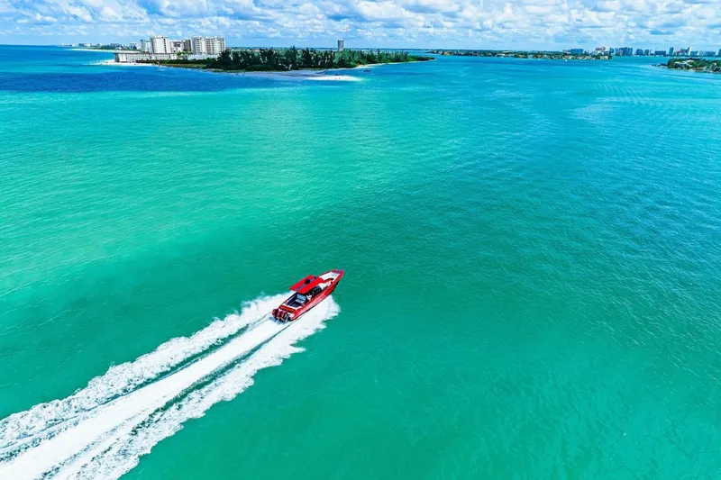 Slide: The Image of Red 2022 Nor-Tech 390 SS boat cruising on turquoise ocean near coastline. - 50