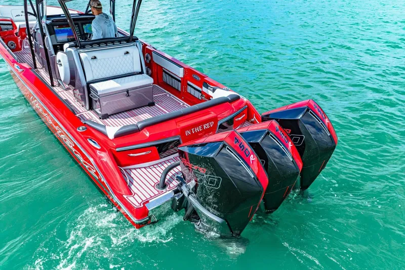 Slide: The Image of Red 2022 Nor-Tech 390 SS boat with triple outboard engines on turquoise water. - 62