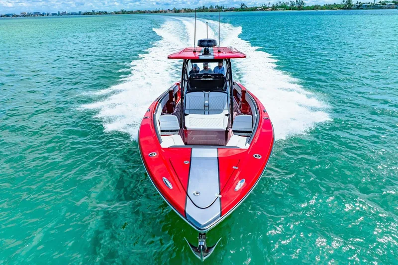 Slide: The Image of 2022 Nor-Tech 390 SS boat cruising on clear turquoise water, showcasing sleek red design. - 66