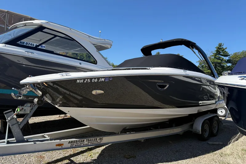 The Image of 2018 Regal 2800 Bowrider boat on trailer, black hull, parked outdoors. - 0