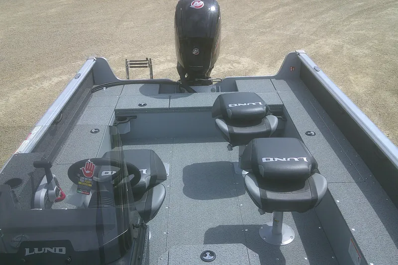 Slide: The Image of 2026 Lund 1800 Explorer SS boat interior with seating and motor, on sandy ground. - 6
