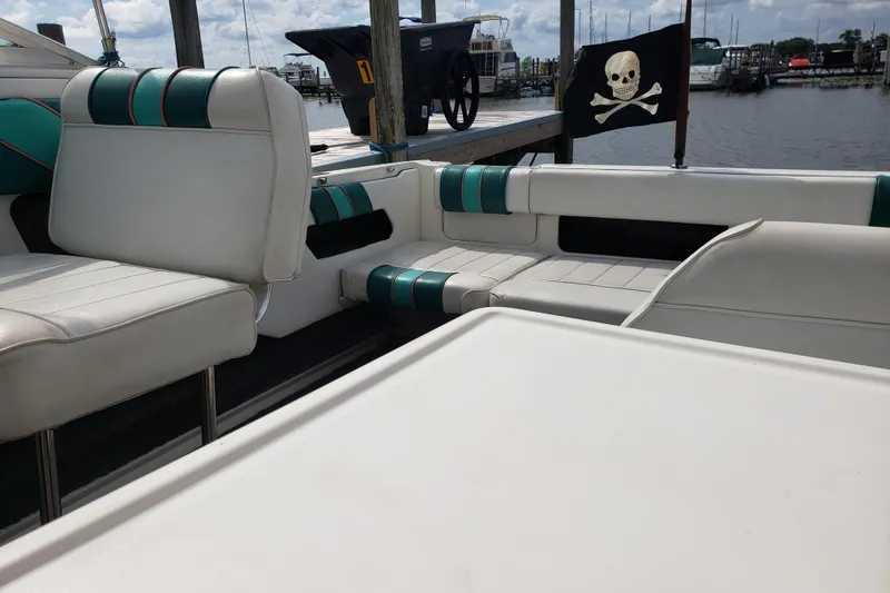 Slide: The Image of 1993 Searay 250EC boat interior with white and teal seating, docked near pirate flag. - 10